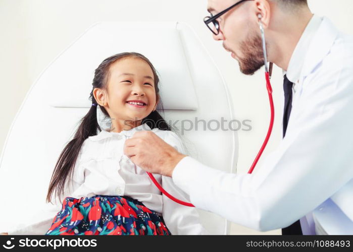 Young male doctor examining little kid in hospital office. The kid is happy and not afraid of the doctor. Medical children healthcare concept.