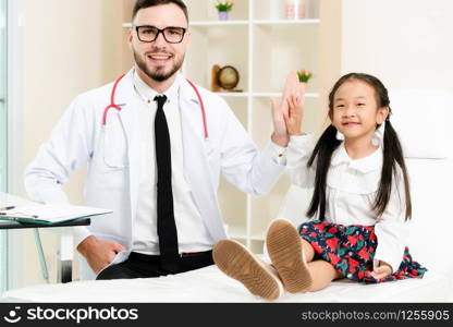 Young male doctor examining little kid in hospital office. The kid is happy and not afraid of the doctor. Medical children healthcare concept.