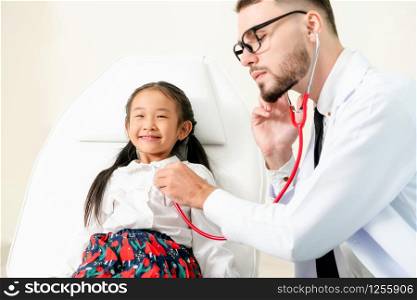 Young male doctor examining little kid in hospital office. The kid is happy and not afraid of the doctor. Medical children healthcare concept.