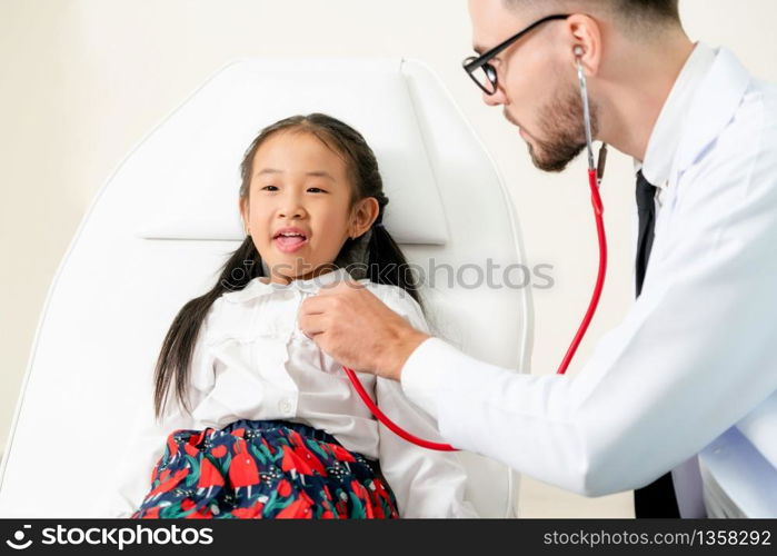 Young male doctor examining little kid in hospital office. The kid is happy and not afraid of the doctor. Medical children healthcare concept.