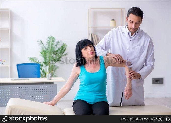 Young male doctor examining old female patient 