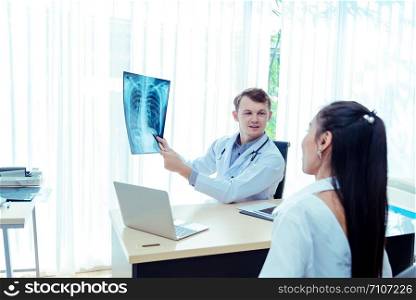Young male doctor explains a sick patient to listen.Examining checking chest x-ray radiography film of patient at ward hospital.Medical surgery and orthopedics health care concept