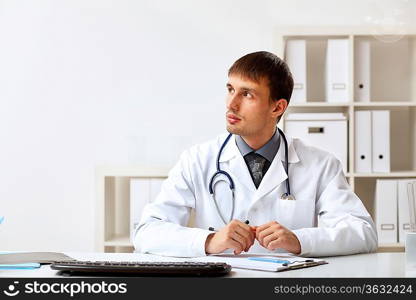 Young male doctor in white uniform at workplace