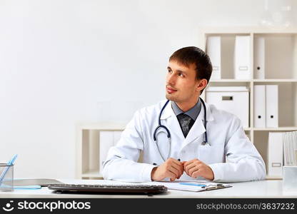 Young male doctor in white uniform at workplace