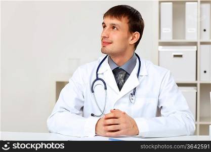 Young male doctor in white uniform at workplace