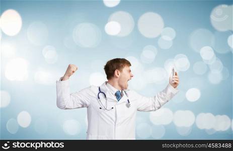 Young male doctor screaming in mobile phone emotionally. Doctor in rage