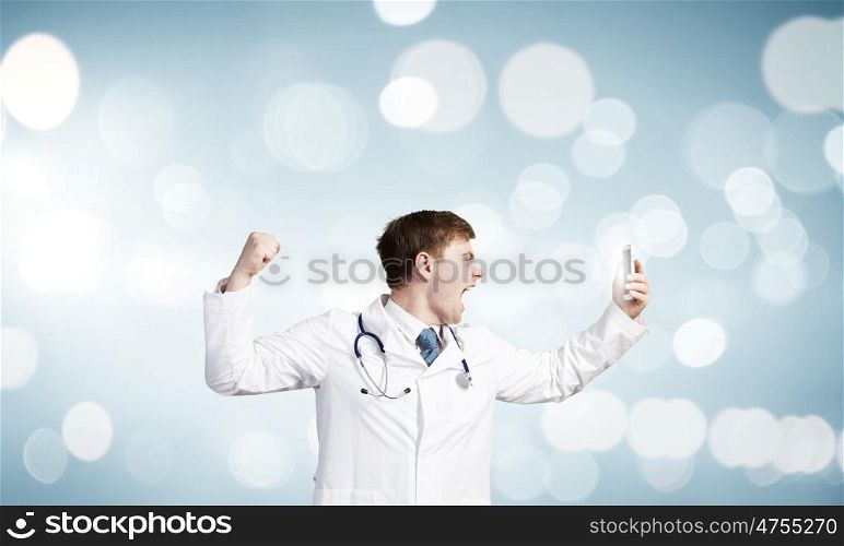 Young male doctor screaming in mobile phone emotionally. Doctor in rage
