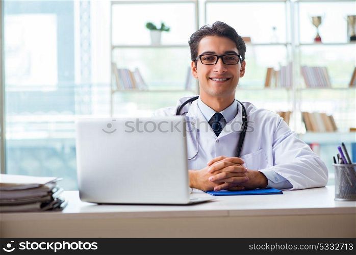 Young male doctor sitting at desk in hospital clinic