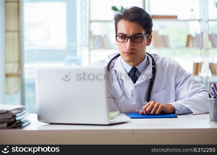 Young male doctor sitting at desk in hospital clinic. The young male doctor sitting at desk in hospital clinic