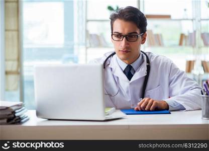 Young male doctor sitting at desk in hospital clinic. The young male doctor sitting at desk in hospital clinic