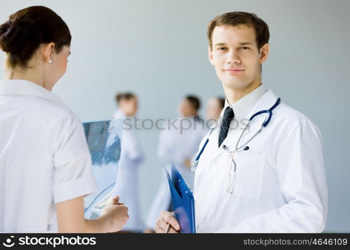 Young male doctor. Young doctor in white uniform talking to colleague