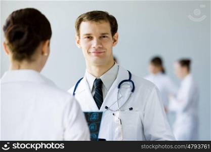 Young male doctor. Young doctor in white uniform talking to colleague
