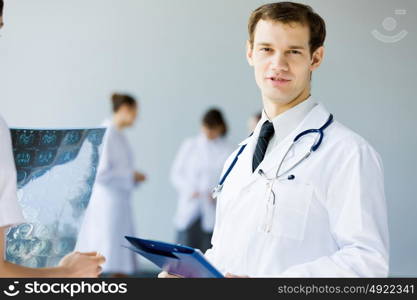 Young male doctor. Young doctor in white uniform talking to colleague