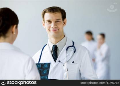 Young male doctor. Young doctor in white uniform talking to colleague