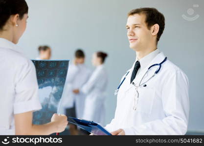 Young male doctor. Young doctor in white uniform talking to colleague