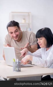 Young male employee explaining to old female colleague how to use computer. Young male employee explaining to old female colleague how to us