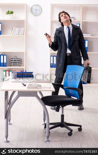 Young male employee in the office in time management concept 