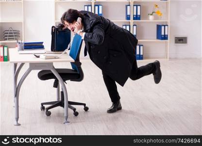 Young male employee in the office in time management concept 