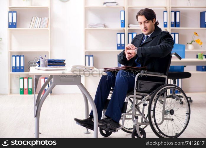 Young male employee in wheelchair working in the office 