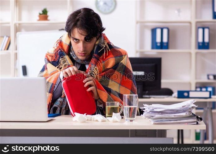 Young male employee suffering at workplace . Man with flu working in the office