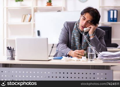 Young male employee suffering at workplace . Man with flu working in the office