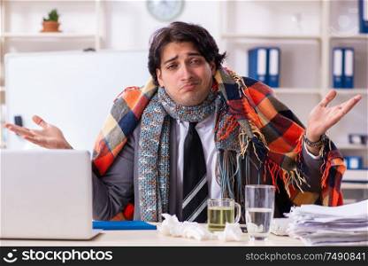 Young male employee suffering at workplace. Man with flu working in the office