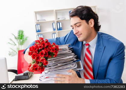 Young male employee with bunch of flowers in the office 