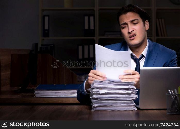 Young male employee working night in the office 