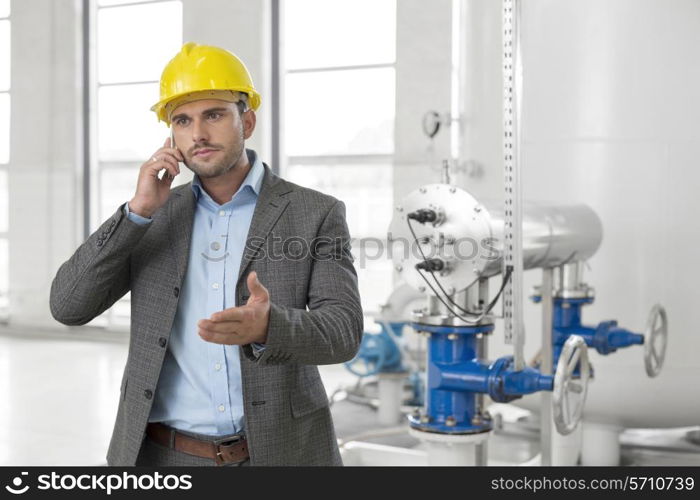 Young male engineer using cell phone in industry