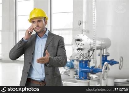 Young male engineer using cell phone in industry