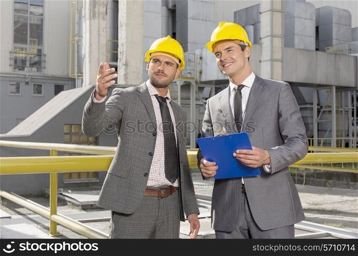 Young male engineers with clipboard discussing outside industry
