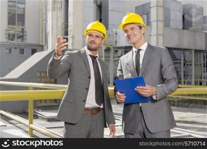 Young male engineers with clipboard discussing outside industry