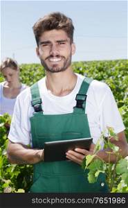 young male farmer holding tablet in vineyard