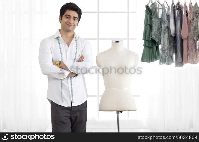 Young male fashion designer standing by mannequin in studio