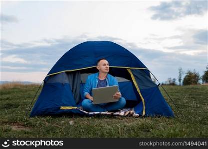 young male freelancer is working on a laptop outdoors in mountains. Freelance concept.. male freelancer is working on a laptop outdoors in mountains. Freelance concept.