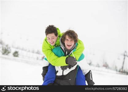 Young male friends enjoying piggyback ride in snow
