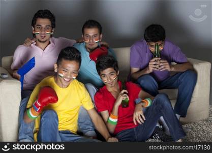 Young male friends watching boxing match together at home