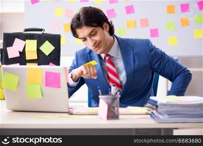 Young male handsome employee in conflicting priorities concept 