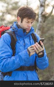 Young male hiker using smart phone in forest