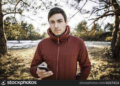 Young male hiker using smartphone in lakeside forest