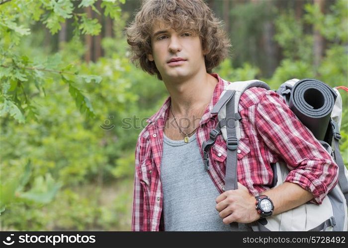 Young male hiker with backpack looking away in forest