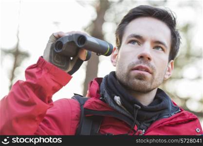 Young male hiker with binoculars in forest