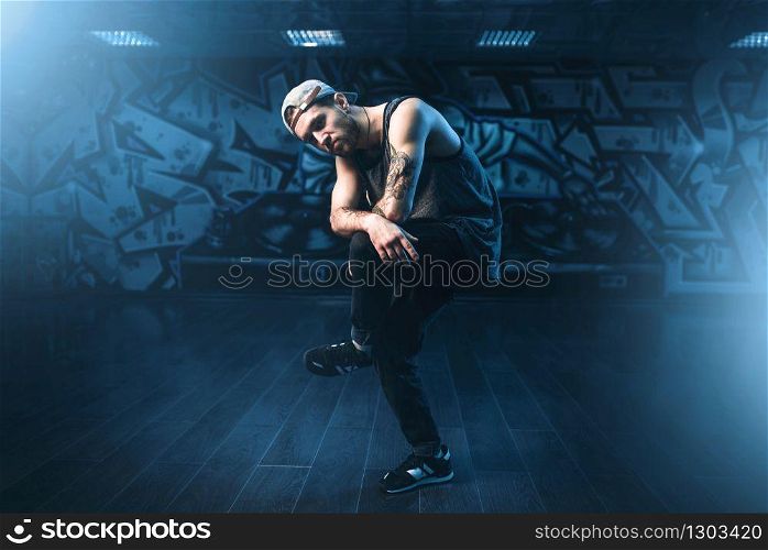 Young male hip hop dancer posing in dance studio. Modern urban dancing style