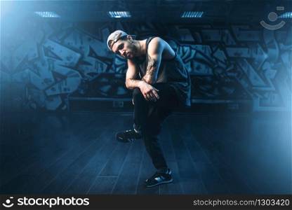 Young male hip hop dancer posing in dance studio. Modern urban dancing style