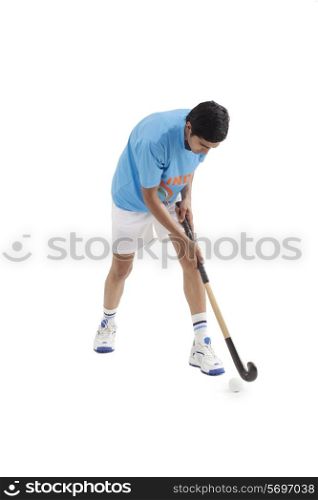 Young male Indian player playing hockey isolated over white background