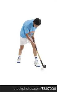 Young male Indian player playing hockey isolated over white background