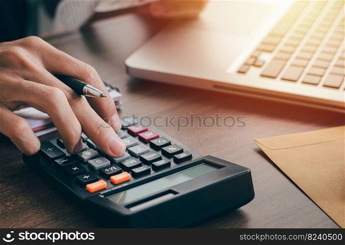 Young male investor calculating investment costs with a calculator and holding banknotes in hand. with business, investment, tax