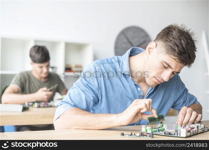 young male it technician fixing ram motherboard slot