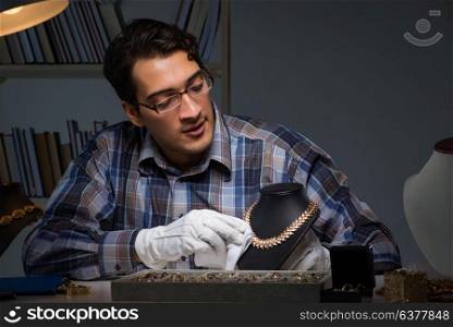 Young male jeweller working at night in his workshop