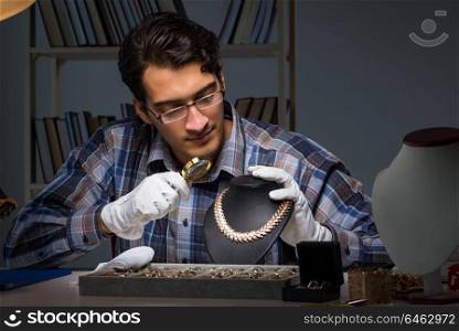Young male jeweller working at night in his workshop
